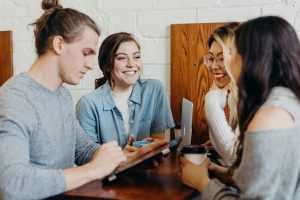 a group of people sitting around a table talking to each other