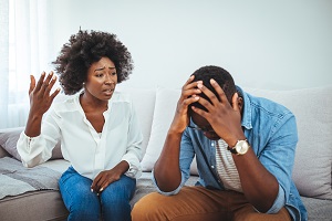 Young couple having argument - conflict, bad relationships. Angry fury woman. Angry young couple sit on couch in living room having family fight or quarrel suffer from misunderstanding