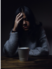 a woman sitting at a table with a cup of coffee is having mental illness