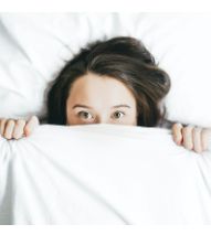 a woman hiding in fear behind a white sheet