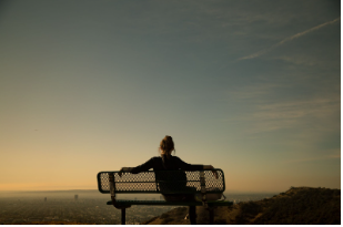 a person sitting on a bench alone during the covid time.
