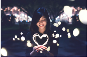 a woman holding a heart shaped object in her hands and looks to be in a happy mood
