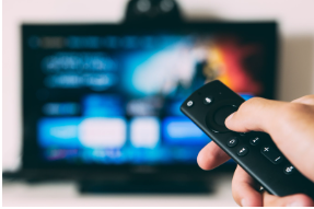 a person holding a remote control in front of a television