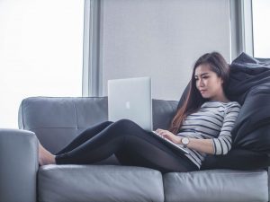 a woman sitting on a couch searching best therapy instruction on her laptop