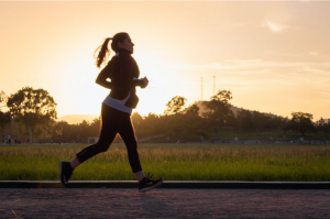 a woman running in a field at sunset to maintain health