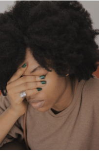 Woman covering her face and looking down. This photo could represent a person experiencing depression and sadness. Therapy for mood disorders in Woodland Hills CA can help with coping with depression using cognitive behavioral therapy. 