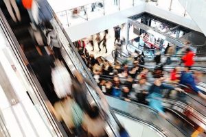 In the mall escalator image, people are rushing and moving swiftly towards their destination, creating a sense of hustle and bustle.