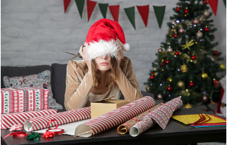 In this image we see a woman during Christmas time, wearing a Santa hat covering her eyes. On the table in front of her we see gifts and wrapping paper, and behind her we see a decorated Christmas tree. Holidays can be a very stressful time, which is why therapy can help you declutter and destress. Individual and couples therapy is offered at our Los Angeles, CA therapy practice. 91364 | 91307 | 91356