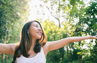 In this image we see a girl in nature, with a smile on her face, and her arms spread outwards. Taking care of your mental health is very important especially during the holidays. We offer individual and couples therapy at our Los Angeles, CA therapy practice.