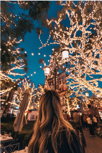 In this image we see a woman looking up at surrounding lights that are covering the trees around her. Individual therapy is available at our Woodland Hills, CA therapy practice for in person or virtual sessions. 91364 | 91307 | 91356