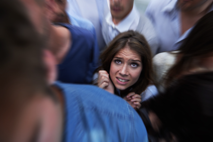 In this image we see a woman stuck in a crowd of people looking distraught. Learn how to set boundaries all year long through individual therapy at our Los Angeles, CA therapy practice with virtual or in person sessions. 91364 | 91307 | 91356