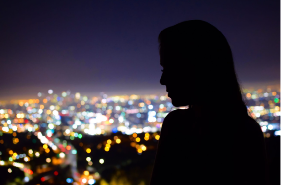 We see the silhouette of a woman and in the background is the city lights during nighttime. Learn how to set boundaries with your friends and family in therapy at our Los Angeles therapy practice.