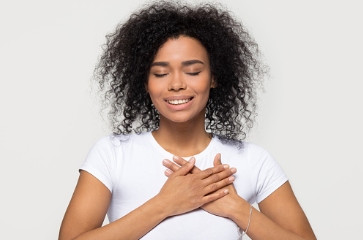 In this image we see a black woman with her eyes closed and her hands covering her heart. Forgiving yourself for your past mistakes is the first step in moving on. CBT therapy can help you learn ways to deal with your negative thoughts which is offered at our therapy office in Woodland Hills, CA. 91364 | 91307 | 91356