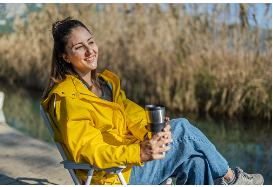 Girl sitting on a chair in nature, by a lake with a thermos in hand wearing a yellow jacket. Spending time in nature can help you practice being present and practice mindfulness. Being present helps lessen stress and anxiety. Anxiety treatment is offered in Woodland Hills, CA with virtual or in person therapy sessions. 91356 | 91301 | 91302