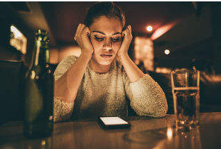 In this image we see a woman sitting at a bar, with her hands on her face, looking down at her phone. Infront of her is a bottle of bear and a glass filled with beer. Anger issues can lead at destructive behavior that can be worked on through CBT therapy. Virtual and in person therapy is available at our Woodland Hills, CA location. 91364 | 91307 | 91356