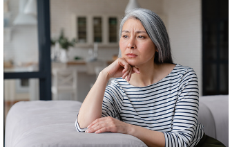 Woman sitting on a couch with white hair with her chin leaning on her hand. She may be experiencing dissatisfaction which is affecting her mental health. You can get help for your mental health at our Los Angeles location with a therapist. 