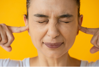 This image shows a woman with her eyes closed, nose crinkled, and fingers in her ears. She is standing in front of a yellow background. This photo can represent this woman not allowing others opinions get to her. You can get help feeling more confident and content through therapy at our Woodland Hills, CA therapy clinic. 91364 | 91307 | 91356 | 91301