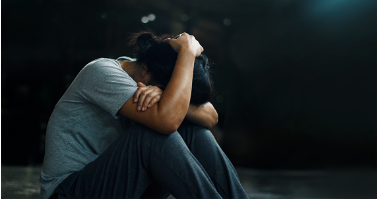 In this image we see a woman sitting on the floor with her head down covered with her arms on her knees. The background is dark and you can sense that she is in distress. Often times when our mental health is declining, we reach a breaking point. Individual therapy is available for virtual or in person sessions at our Woodland Hills therapy office. 91356 | 91301 | 91302