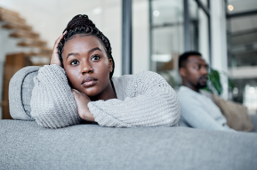 In this image we see a young black man and black woman sitting together on the couch. In the distance we see the man, and up close we see the woman turned away from the man with her hand on her head. Communication is key in any relationship and can help both parties feel heard and understood. Learn how to effectively commmunication in your relationship with couples therapy available at our Woodland Hills, CA therapy practice. 91364 | 91307 | 91356
