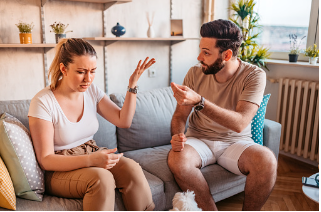 In this image we see a couple arguing with one another sitting on the couch. They are both visibly upset with one another and seem to be in conflict. Constantly blaming your partner without taking accountability for yourself may be a sign that there are issues in communication between you and your partner. Couples therapy is offered virtually or in person for therapy sessions at our Woodland Hills, CA therapy practice. 91364 | 91307 | 91356