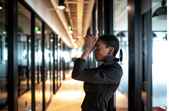 An African American woman is standing in an office hallway leaning against the wall with her hands on her forehead. Not being able to cope with your fears is a sign that you may have a fear of failure. Guidance on how to cope with your fear of failure is offered at our Woodland Hills therapy practice, virtually or in person. 91364 |91307 |91356