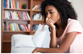 Young black teenage girl is seen sitting on a white couch with a library behind her. She seems upset with her hand covering her mouth. A change in mood can be a sign of your teen's anxiety getting worse. Anxiety therapy for teenagers is offered at our Woodland Hills therapy clinic. 91356 | 91301 | 91302
teen's anxiety
