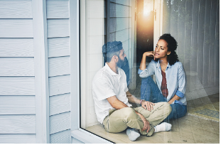A man and woman are seen sitting on the floor near a window together. The man is sitting with his legs crossed while the woman is facing him with her hand under her chin. Being vulnerable with your partner can help establish a raw and honest relationship with one another. We offer virtual and in person couples therapy sessions at our Los Angeles, CA therapy practice. 91364 | 91307 | 91356