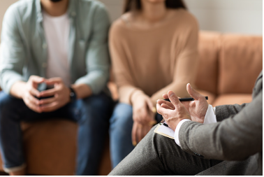 a couple sitting in a therapy office listening to a therapist discussing their relationship issues. A couple's therapist can help you address the issues in your relationship and resolve lack of trust and disconnection, teach you better skills to connect and prosper in your marriage. Call today