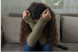 Teenage girl with curly hair is seen sitting on a grey couch with her head down and her arms crossed covering her face on her legs. The feeling of grief and loss is common amongst teenagers due to the pandemic. Take your teenager to anxiety therapy at our Woodland Hills therapy office for virtual therapy or in-person therapy. 91301 | 91302
teen's anxiety