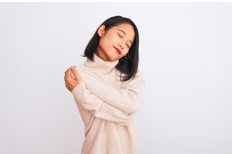 In this image we see an Asian woman with her arms wrapped around herself giving herself a hug. Being compassionate with yourself can help you overcome your fear of failure. Virtual and in person therapy is offered at our therapy practice in Woodland Hills, CA. 91364 | 91307 | 91356