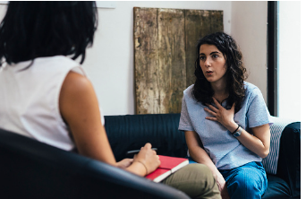 A woman in therapy sitting on a couch and talking to a therapist while talking. The therapist has a notebook and listening. If your relationship issues has made you anxious and depressed, our CBT therapist can help you learn the effective relationship skills for better communication and conflict resolution skills. Call for a phone consultation for individual therapy
