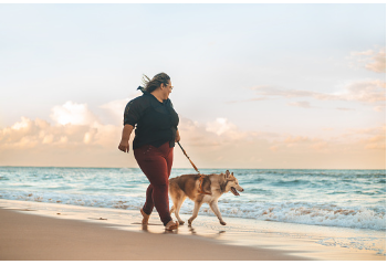 A woman is at the beach taking a walk with her dog. Finding things you enjoy doing and engaging in coping skills can help you regulate your mental health and feel better overall. We offer virtual and in person therapy sessions for individuals who are living in the Woodland Hills, CA area. 91356 | 91301 | 91302