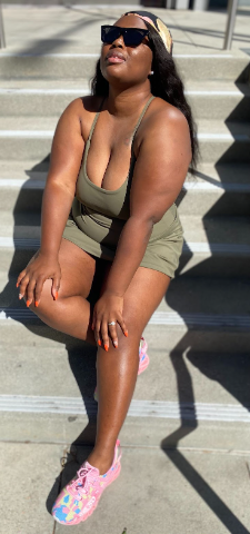 African American Woman relaxing on some stairs in the sun. She is enjoying the summer sun, carefree and not anxious about her summer plans and goals. 