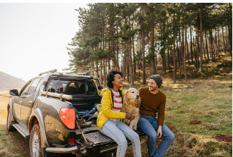 a couple sitting in the back of their truck with their dog while on an outdoor location. Couple's therapy can help you and your partner learn to enjoy each other's company and have fun together again. Call today for relationship counseling in person or online in Woodland Hills, CA 91364