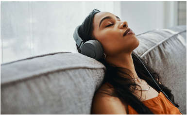Shot of a young woman using headphones while relaxing on the sofa at home. Feeling better and more hopeful is possible with help from an anxiety therapist in Los Angeles, CA for anxiety treatment via online therapy in California. 91307