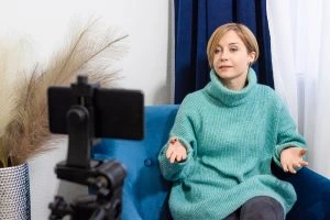 This image shows a woman with her phone set up as a camera on a tripod. This image may depict a woman attending her therapy session online. Embracing You Therapy offers both online and virtual therapy sessions to suit all your needs.