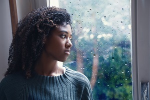 Black woman feeling depression symptoms alone at home.