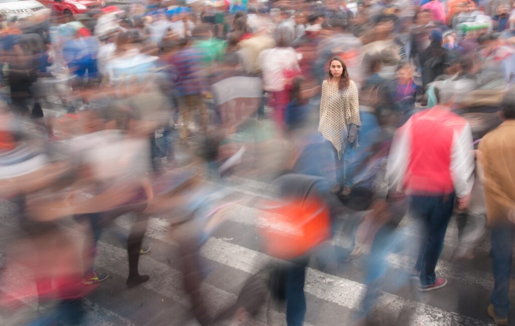 A woman sitting in the middle of a cross walk in a busy interaction where people are crossing the street. This photo represents feeling lost and confused in an overwhelming schedule. You can get help for depression and anxiety by learning CBT tools like thought-recording from a counselor in Woodland Hills, CA here in person or online therapy in California. 91344