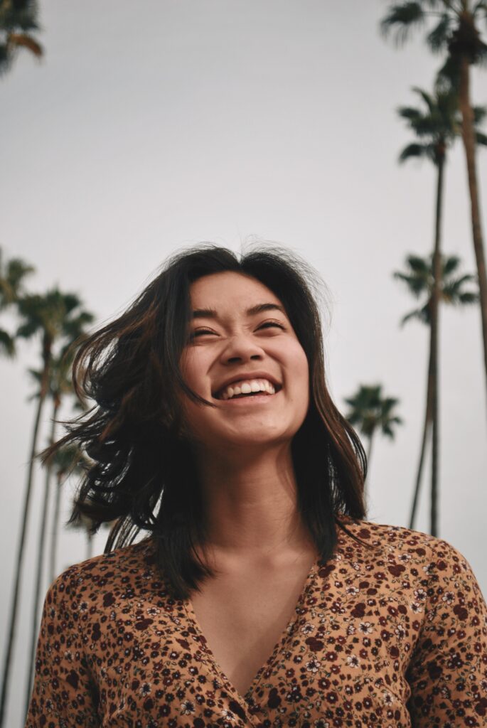 An Asian American woman standing outside and smiling. This photo represents feeling self-confident, fulfilled, and content. If you are struggling with low self-esteem, feeling insecure and overwhelmed, CBT therapy with one of our anxiety therapists in the Woodland Hills office can help. Call today.