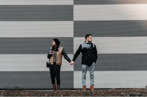 Couple holding hands against a striped background. You can get couples therapy and marriage counseling in Los Angeles, CA or via online therapy in California with a certified marriage counselor in Los Angeles, CA. 
