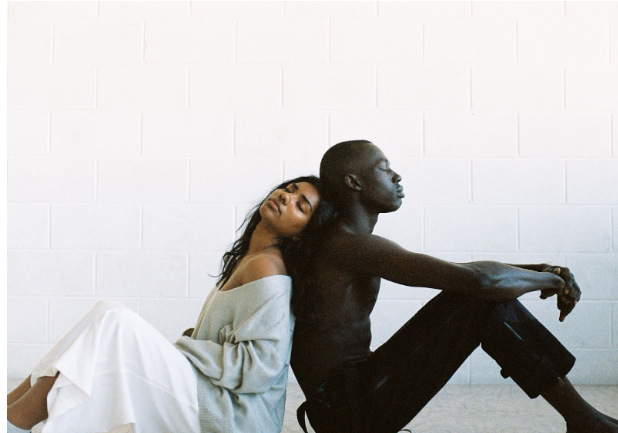 Couple sitting back to back, looking relaxed and comfortable.