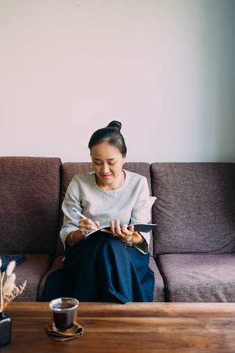 Young Asian woman sitting comfortably on the couch in her living room, writing in her notebook. You can get help from an anxiety therapist in Los Angeles, CA for anxiety treatment to help with overcoming obsessive-compulsive disorder in Los Angeles, CA too. 91364 | 91307 | 91356 | 91301 | 91302 | 91372
91367 