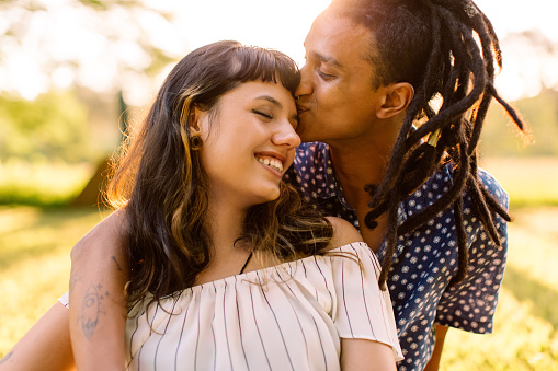 Beautiful young interracial couple being romantic while sitting in a park. Affectionate young man kissing his girlfriend on her forehead while embracing her during the day.  You can feel this free after couples therapy and marriage counseling in Los Angeles, CA with a marriage counselor via online therapy in California here.  91364