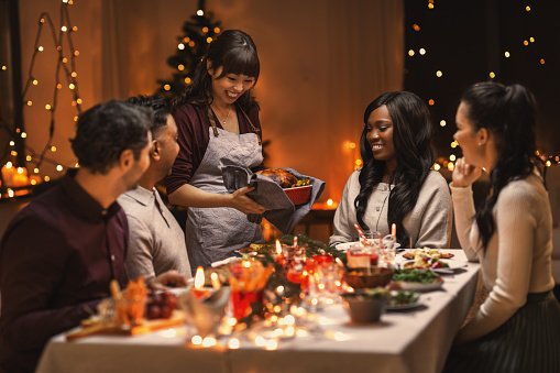 Holidays and celebration concept - multiethnic group of happy friends having Christmas dinner at home. If you are struggling with holiday stress and anxiety, you can get help from an anxiety therapist in Woodland Hills, CA for anxiety treatment to improve your mood, self-esteem, and codependency in Woodland Hills, CA too. 90077 | 91324 | 91364 | 91411 | 91436 
