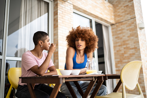 A couple having breakfast in the balcony at home facing each other as they have a conversation. Feeling better and more hopeful in your couple's relationship today with the help of marriage counselors in Woodland Hills, CA and available online. 