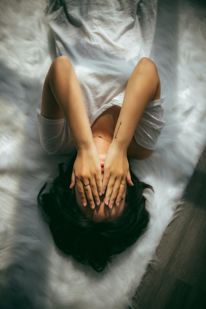A woman laying in her bed and covering her face with two hands feeling shame and guilt. This photo could represent a person experiencing anxiet.  Learn to forgive yourself, along with Anxiety treatment in Woodland Hills, CA can help with coping skills by talking to an anxiety therapist. 91364