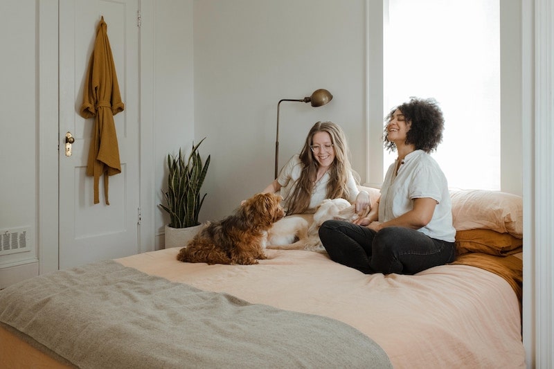 two women hanging out on a bed with a dog