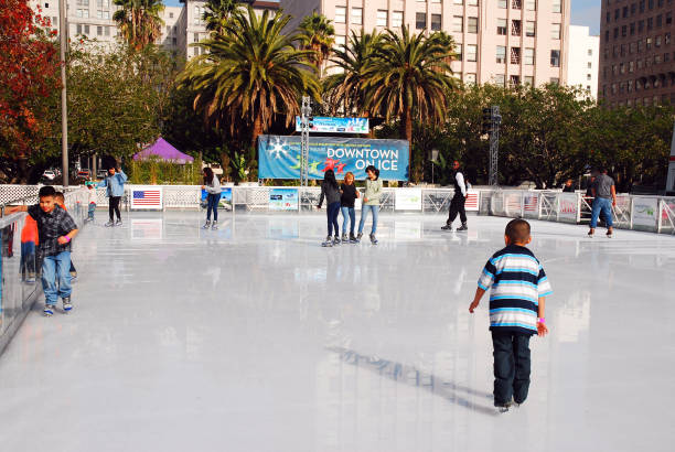 In this image we see the Downtown Los Angeles ice rink. There are children ice skating outdoors. Parenting Tips