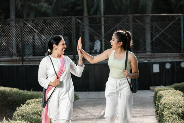 A mother and daughter are going on a hike together. They are walking side by side with a smile on their faces as they high-five each other.