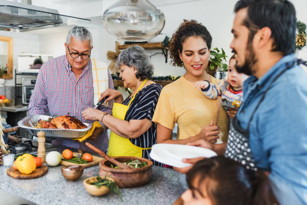 A Latin American family is cooking in the kitchen together on Thanksgiving. They are all smiling and happy.